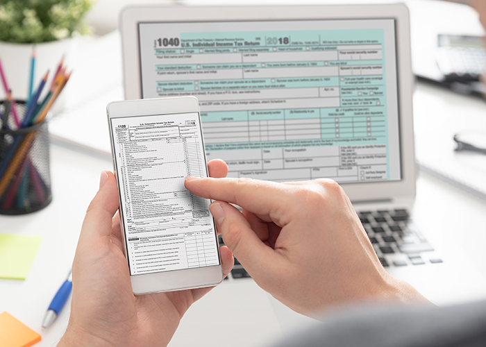 Accountant are filling online tax information using smartphone and laptop. Tax income concept