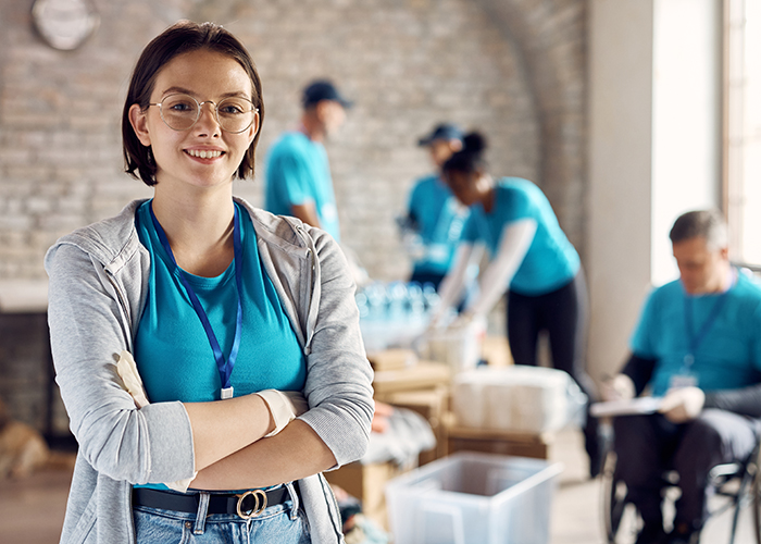 Portrait of happy volunteer coordinator with arms crossed at community center.