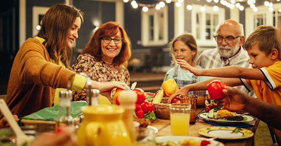 Group of Multiethnic Diverse People Having Fun, Communicating with Each Other and Eating at Outdoors Dinner. Family and Friends Gathered Outside Their Home on a Warm Summer Evening.