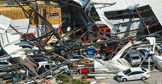 Hurricane Ian destroyed industrial building with damaged cars under ruins in Florida. Natural disaster and its consequences