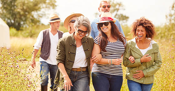Group Of Mature Friends Walking Along Path Through Yurt Campsite
