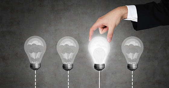 A hand chooses one lightbulb out of four other. A metaphor of the right decision.