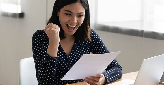 Amazed young multiracial female student hold official written letter with good test exam results. Happy asian woman look at paper document celebrate admission to university receive grant scholarship