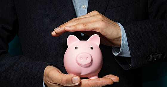 Piggy bank between two palms of man in a business suit hands.